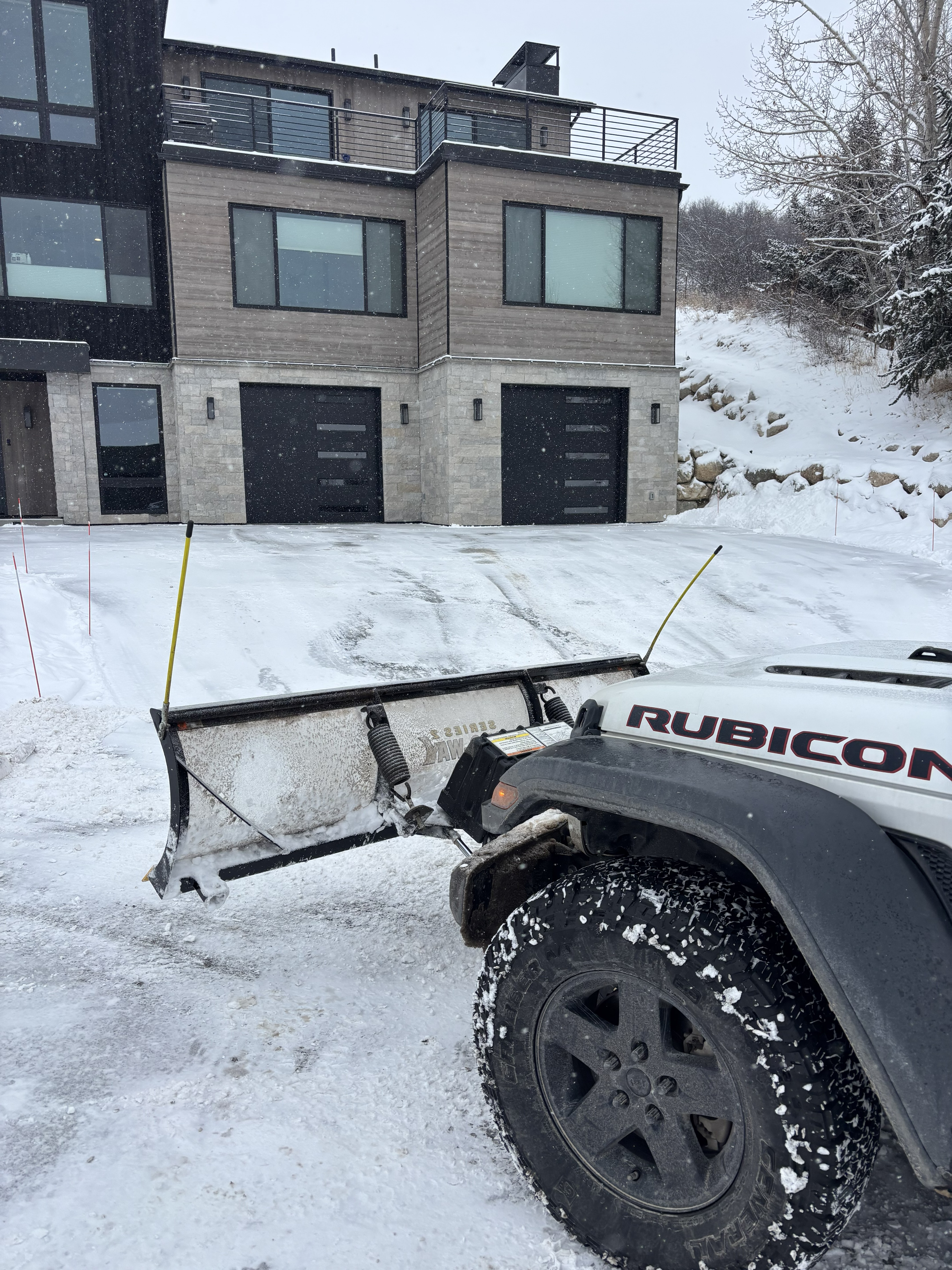 Jeep Rubicon plow clearing driveway at modern luxury home — Eagle County Colorado